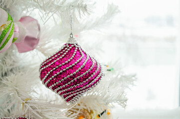 Christmas tree toy purple ball on snow-covered fir branches. shiny sequined figurine hangs on a Christmas tree covered with frost.