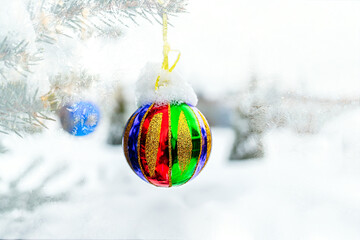 Christmas tree in the snow, a bright rainbow Christmas ball hanging on a tree. Christmas background with copy space