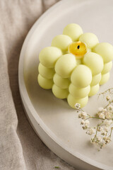 One white square bubble candle on a concrete tray on a linen table cloth with a blooming branch, close-up
