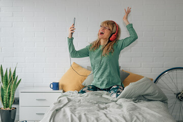 happy woman listening to music at home with headphones and mobile phone