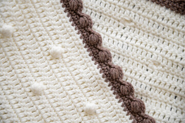 Crochet product from multicolored threads. Handmade backdrop. Flat lay. Fragment of a plaid of brown and ivory tone.