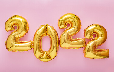2022 gold balloons text on pink color background. Happy New year 2022 lettering eve celebration. Merry Christmas banner