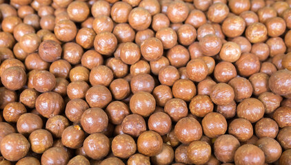Macadamia nuts are a lot of pile as a background and texture. The concept of useful foods and proper nutrition, natural vitamins and minerals not cleaned in the shell, antioxidants