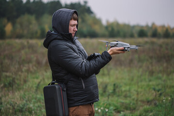 Man holding drone and remote control against field background