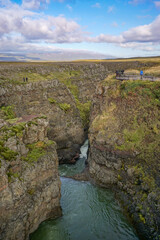 Fototapeta na wymiar Bakkavegur, Iceland: Visitors at Kolugljufur Canyon, near the Kolufossar Waterfalls, on the Vididalsa River.