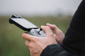 Man holding drone remote control against field background