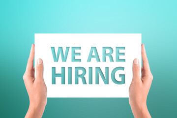 We Are Hiring concept with hands holding the white paper on abstract background