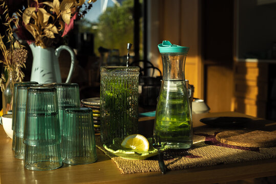 Glasses and glass jar with fresh water, mint and lemon
