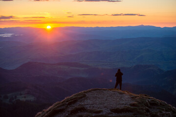 Man in top of mountain photographing the beautiful landscape at sunrise