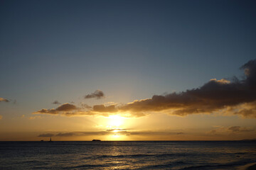 Obraz premium Orange Sunset with purple clouds over a scenic view of the Pacific Ocean off the coast of Waikiki Beach in Hawaii