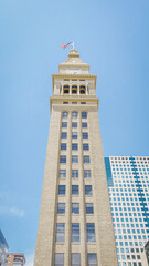 Tall historic landmark brick tower rises up to clear sunny blue sky in downtown Denver, Colorado