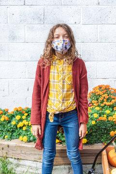 Happy girl wearing protective face mask with fall pattern