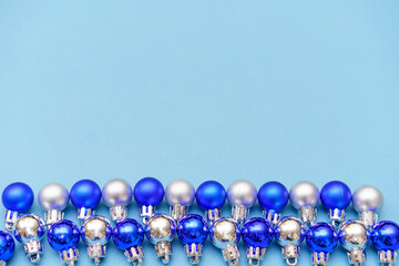New year's composition. Christmas balls of blue and silver color lie in a row on a blue background. Flat lay, top view, copy space