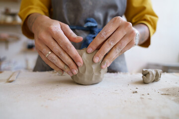 Work with your hands: closeup of creative woman molding raw clay before sculpturing and shaping pottery or ceramics in potter art studio during master class or workshop. Craft and craftswoman concept