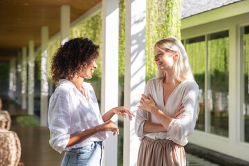 Two Women Smiling at Each Other Standing in Shaded Area