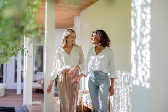 Two Women Standing, Smiling, and Talking Together