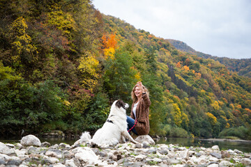Naklejka premium woman with dog enjoying autumn nature by the lake