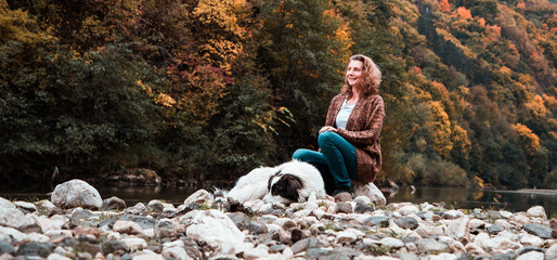 woman with dog enjoying autumn nature by the lake