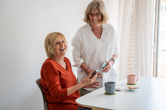 Mature friends at home looking at phone and talking