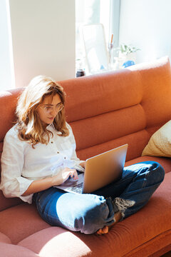 woman with laptop working while sitting on the couch