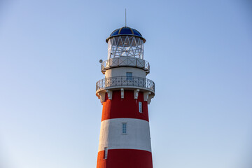 Lighthouse in red and white colors on the seashore, river bank or lake shore. Lighthouse hotel in a fishing village. Travel and tourism concept. Russia, Ryazan region, near the village Shumash.