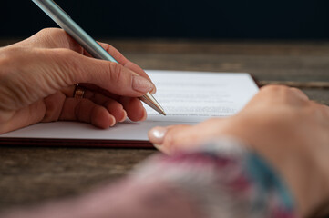 Female hand signing a document, application form