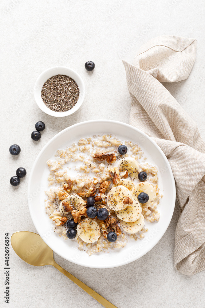 Wall mural Oatmeal bowl. Oat porridge with banana, blueberry, walnut, chia seeds and almond milk for healthy breakfast or lunch. Healthy food, diet. Top view.