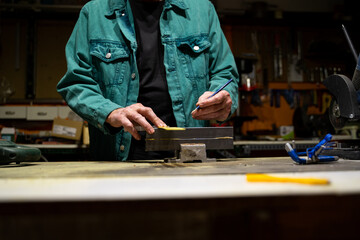 Detail of senior hands measuring metal in garage workshop