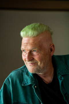 Portrait of cool smiley senior man with green mohawk 