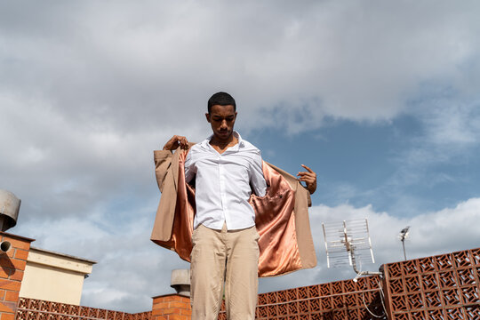 Dandy man putting on his jacket at rooftop