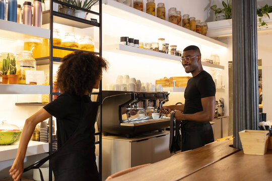Black waiter and waitress working together in cafe