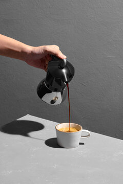 coffee poured from a flying moka into a cup isolated on gray table