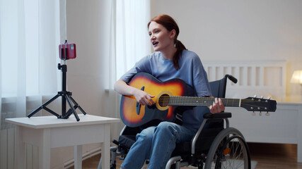 A disabled lady is playing the guitar and singing songs