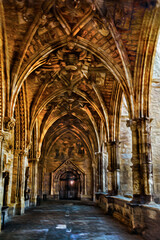 Fototapeta premium Passageway with columns and ceiling in gothic style on a building of Leon. An ancient town on countryside of Spain. Oil paint filter.