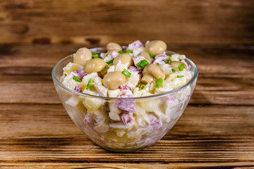 Salad with marinated mushrooms, sausage, onion, boiled potato and mayonnaise on a wooden table