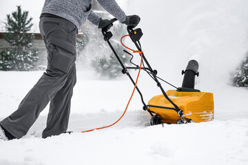 Man with machine removing snow in yard