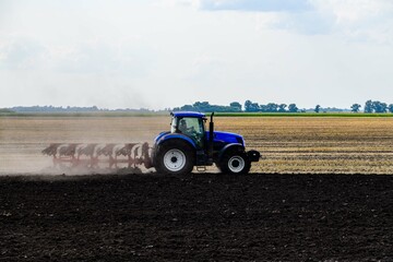 Fototapeta premium Tractor plowing field with the harrow. Agricultural concept