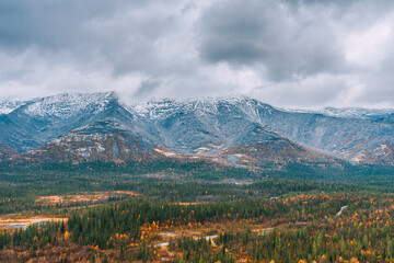Autumn arctic landscape. View of the misty snow-capped mountains and autumn colorful tundra in the Arctic,Kola Peninsula. Mountain hikes and adventures. Austere, cold atmosphere. 