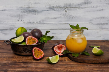 Gulupa or passion fruit juice surrounded by peels and whole and cut fruits, lemons and spearmint on...