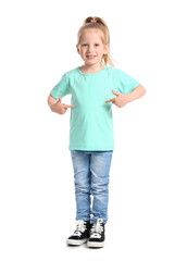 Little girl with ponytail pointing at blue t-shirt on white background