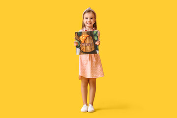 Cute little girl with book on yellow background