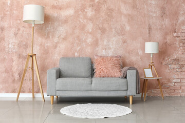Comfy grey sofa and lamps near pink wall