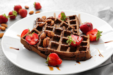 Plate of delicious Chocolate Belgian Waffles with strawberry and almond on light background