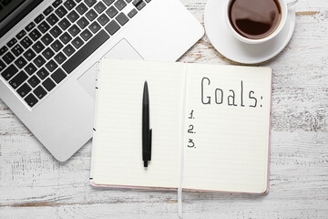 Notebook with empty to do list and laptop on white wooden background. New year goals