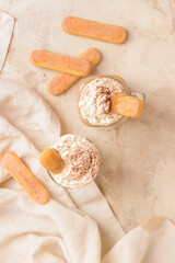 Mason jar and glass of tasty Tiramisu Latte on light background
