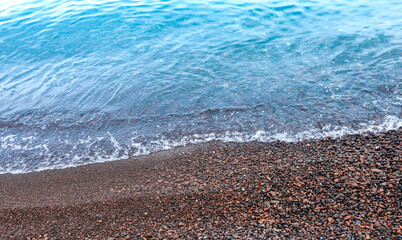 Top view of crystal clear tropical lake with wave swash over pebbles beach selective focus. Seascape view on vacations concept. Tranquility, idyllic and calmness of nature. Landscape background