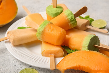 Plate with tasty melon popsicles on light background