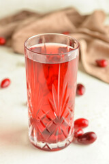 Glass of healthy dogwood berry drink on light background