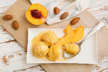 Plate of tasty peach ice cream on white wooden background