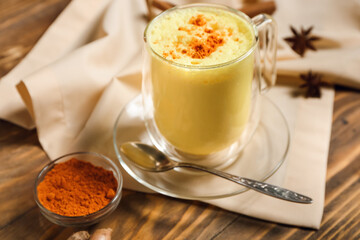 Cup of healthy homemade turmeric latte on wooden background, closeup